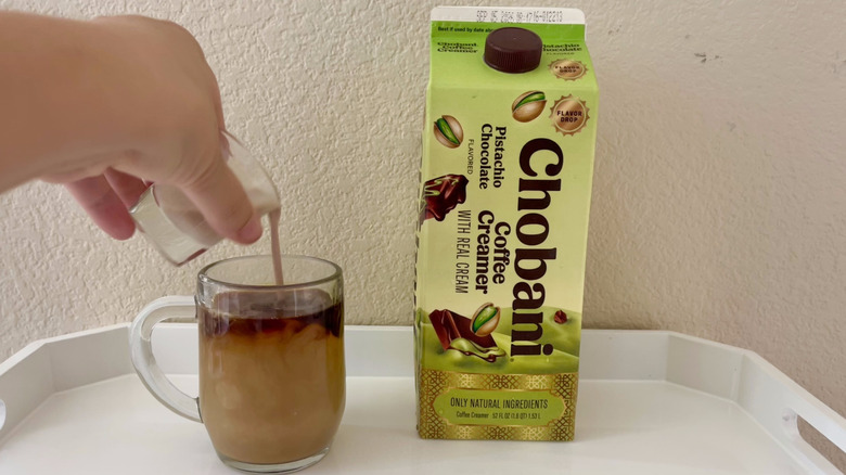 Person pouring creamer into coffee
