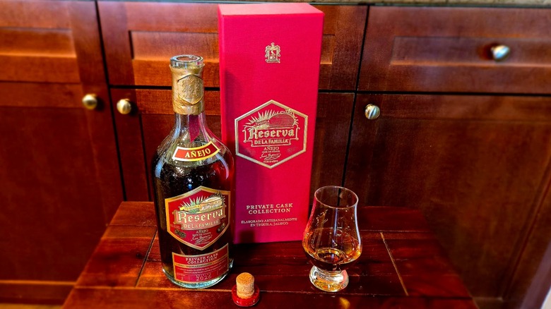 Bottle of Reserva de la Familia with the box and a glass in front of a wooden
