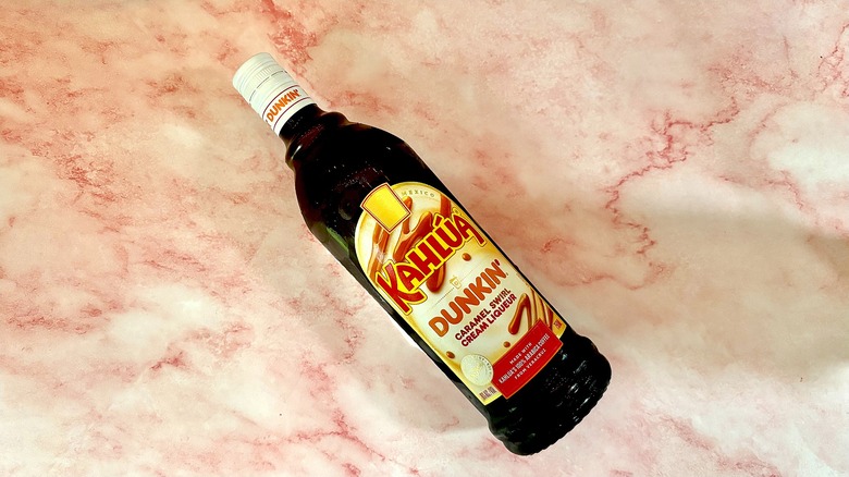 Bottle of Kahlúa Dunkin' Caramel Swirl Cream Liqueur on pink marble surface