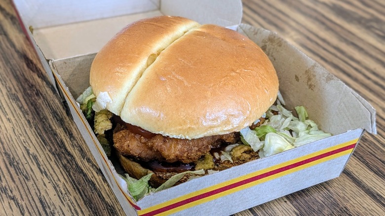 A McCrispy in a paper box on a wood table