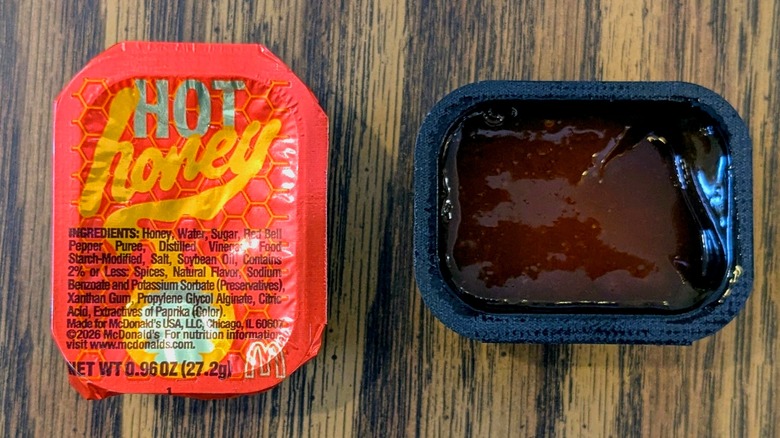 A close-up of a sealed and an open container of McDonald's Hot Honey Sauce