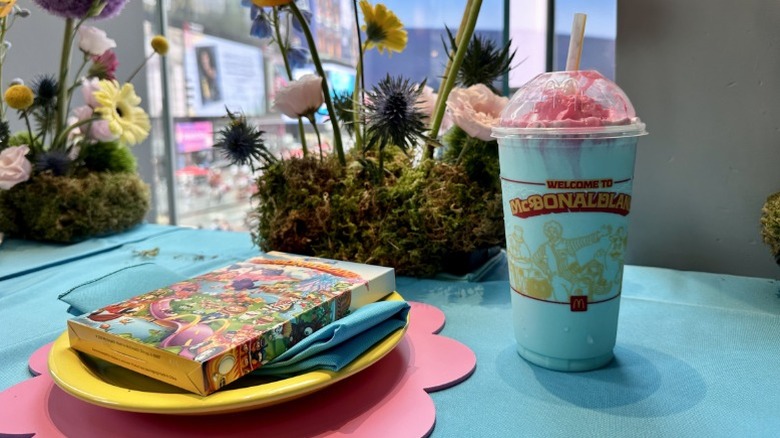A Mt. McDonaldland Shake on a table next to a commemorative tin
