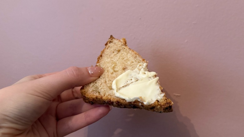 hand holding scone with clotted cream on it