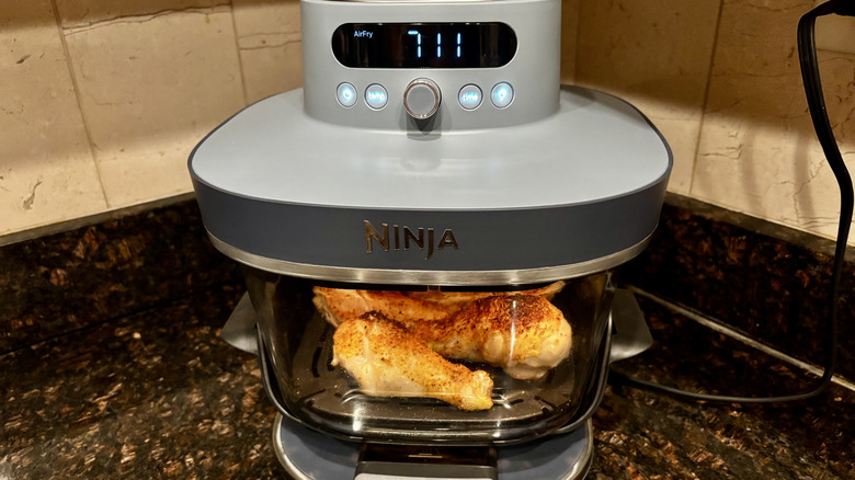 Ninja air fryer with chicken drumsticks cooking inside