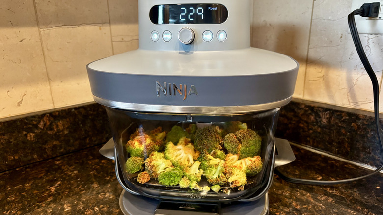Broccoli cooking inside of a glass Ninja air fryer basket