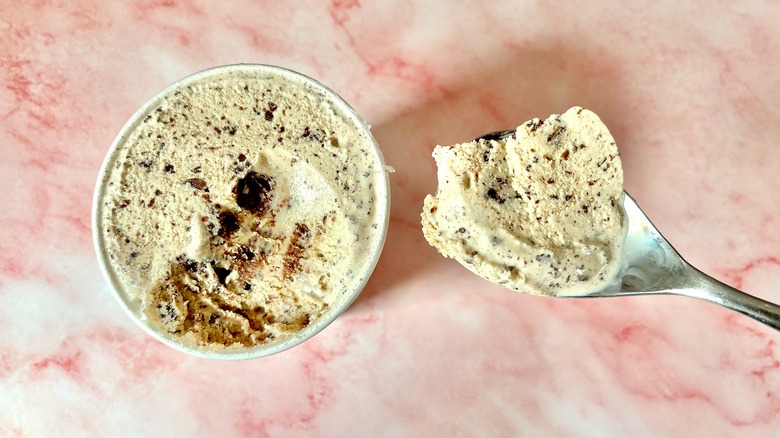 Top-down view of Chocolate Chip Zucchini Bread Salt & Straw pint next to spoon on pink marble surface