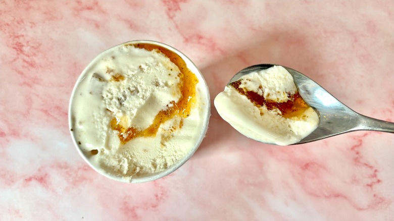 Top-down view of Miso Blondies with Basil Peach Jam Salt & Straw pint next to spoon on pink marble surface