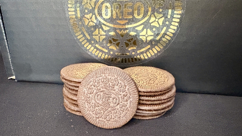 Oreo thins stacked in front of box with gold logo