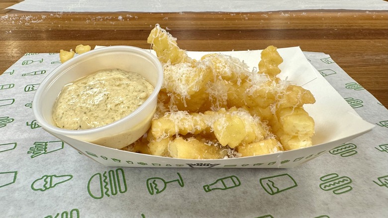 Shake Shack's Garlic Parmesan Fries dusted with fresh parmesan on a patterned paper placemat