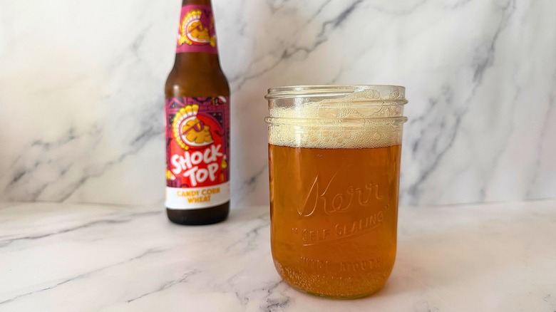 Shock Top Candy Corn Wheat Ale in Mason jar, bottle blurred in background on marble surface