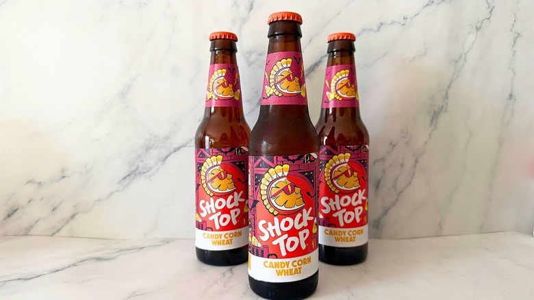 Three bottles of Shock Top Candy Corn Wheat Ale on marble surface
