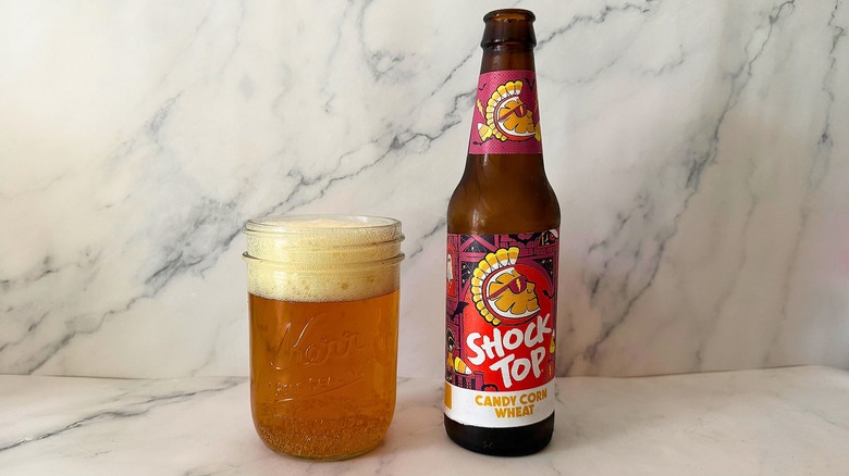 Shock Top Candy Corn Wheat Ale bottle next to ale in Mason jar on marble surface