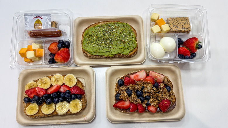 Three loaded toasts and two plastic snack boxes on a wooden table