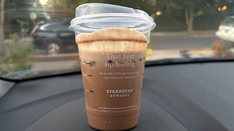 To-go cup with Starbucks Iced Chocolate Cream Protein Cold Brew on dashboard in car