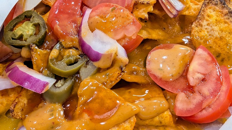 A close-up of Doritos Hot Honey Nachos with jalapenos, onions, tomatoes, and cheese