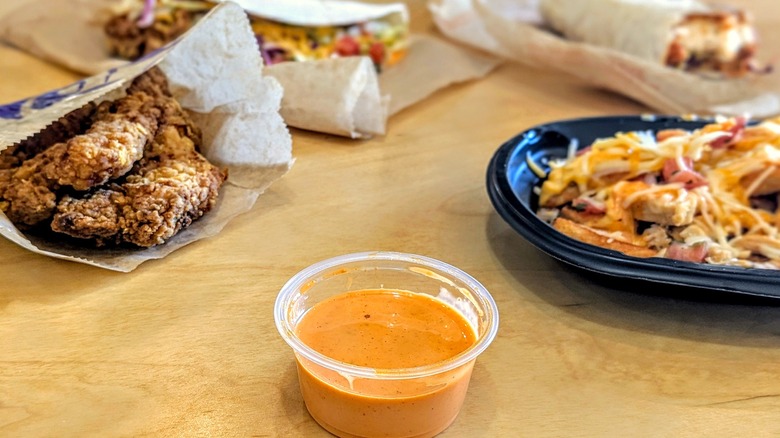 Cup of Taco Bell Frank's RedHot Diablo Sauce with menu items in the background