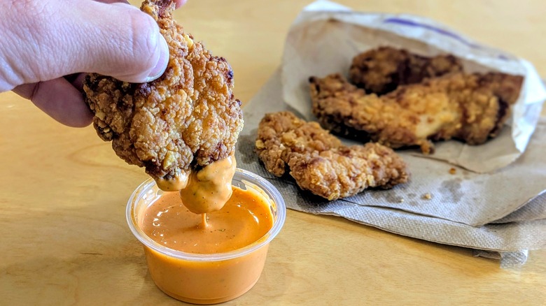 Taco Bell Crispy Chicken Strips being dipped into Frank's RedHot Diablo Sauce