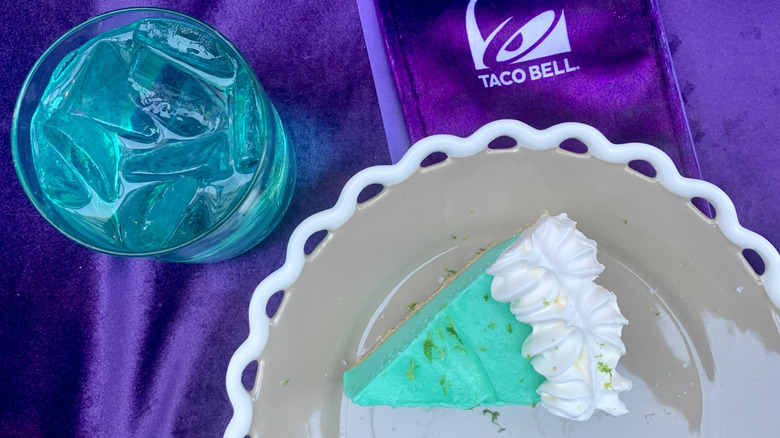 A slice of Taco Bell Mountain Dew Baja Blast Pie next to a glass of the eponymous soda