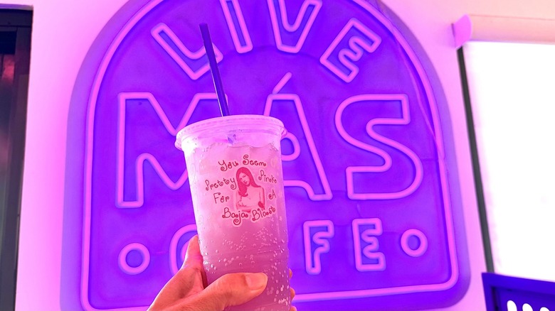 hand holding "You Seem Pretty Pink for a Baja Blast" in front of Live Mas Cafe sign