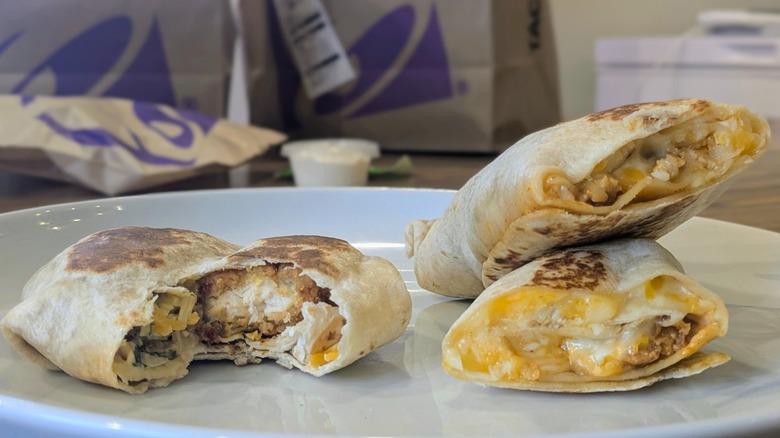 A close-up of cross-sections of a Crunchwrap Slider and a Rolled Quesadilla on a white plate