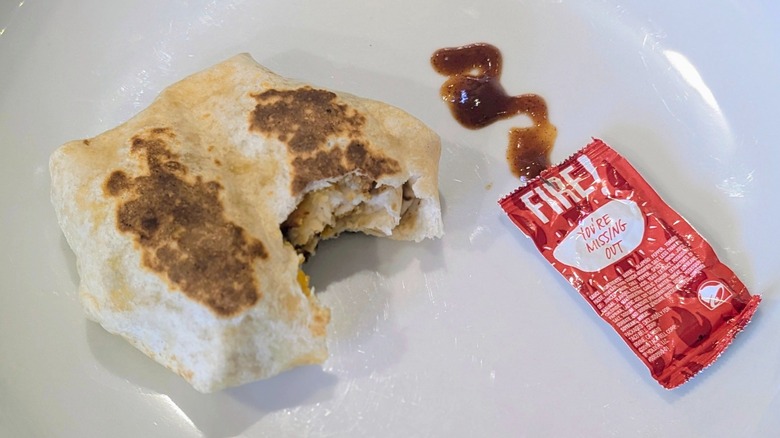 A Crispy Chicken Crunchwrap Slider with a packet of Fire sauce on a white plate