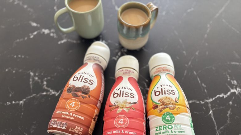 Natural Bliss coffee creamer bottles on countertop with cups of coffee