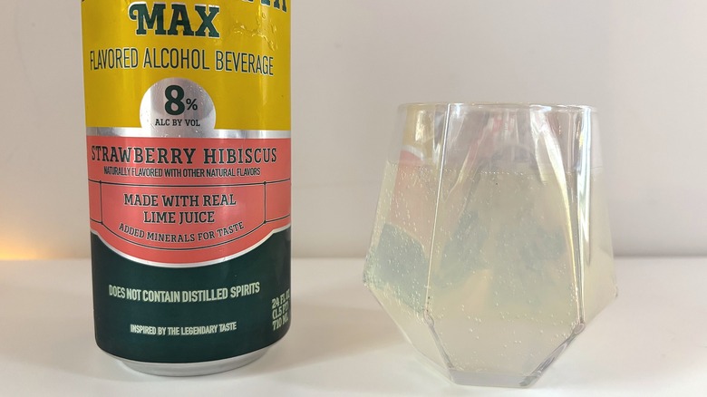 Close-up of glass of Topo Chico Margarita Max next to can of margarita on white table