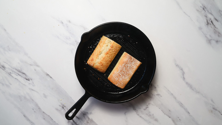 Ciabatta buns toasting in a cast iron pan