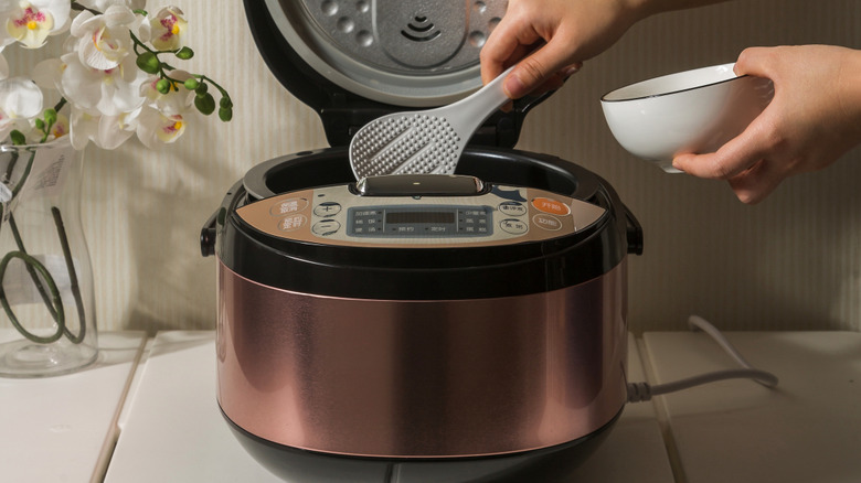 Rice cooker with hand reaching for rice