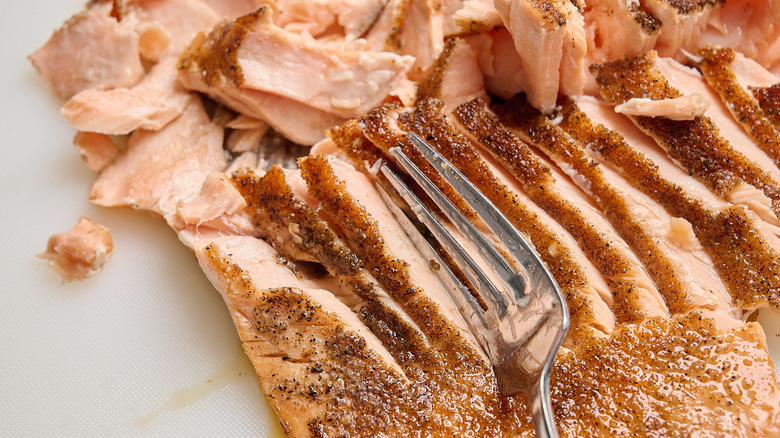 flaking salmon into pieces with a fork