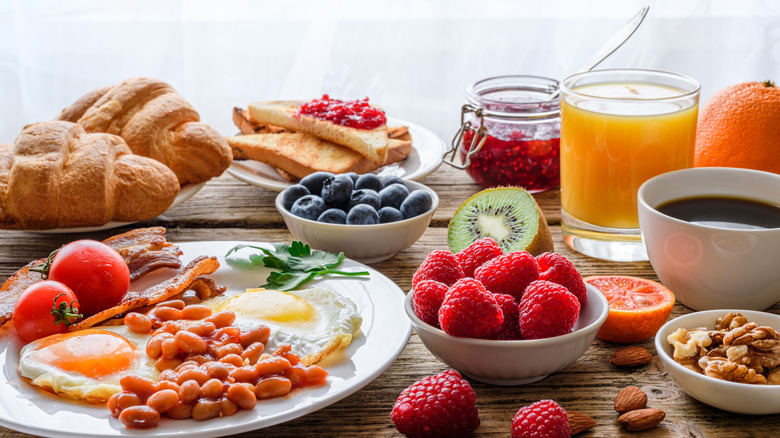 Hotel breakfast with croissants, fresh fruit, nuts, eggs, beans, and orange juice