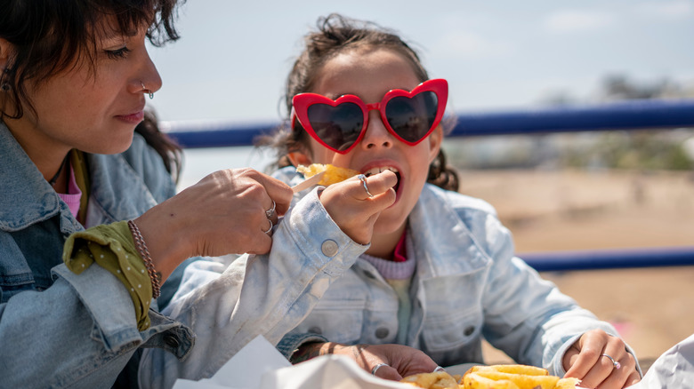 Mother and daughter eating fish and chips at seaside