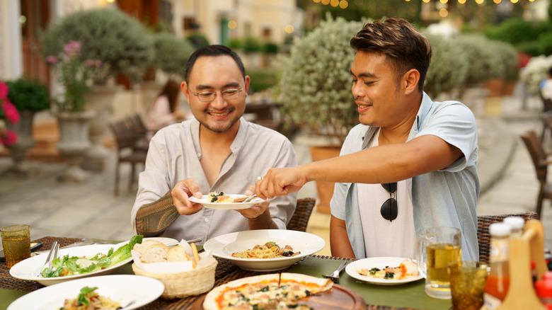 two men enjoying food outside at a restaurant