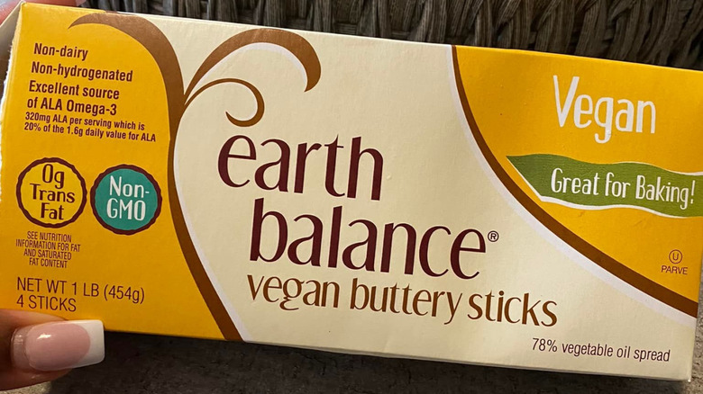 hand holding Earth Balance Vegan Buttery Sticks on table