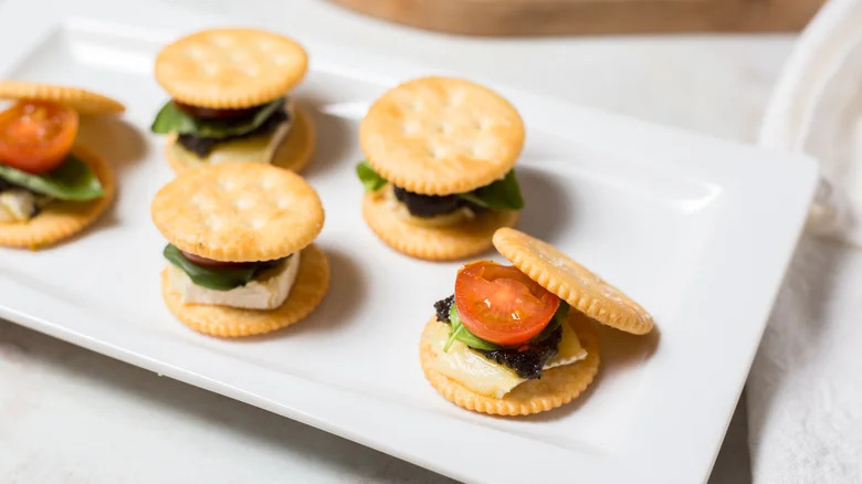 Plate of Brie crackers with spinach and tomato