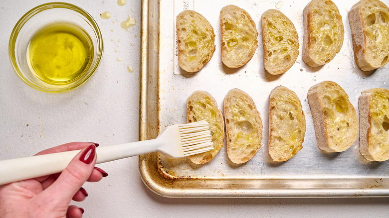 brushing olive oil onto crostini