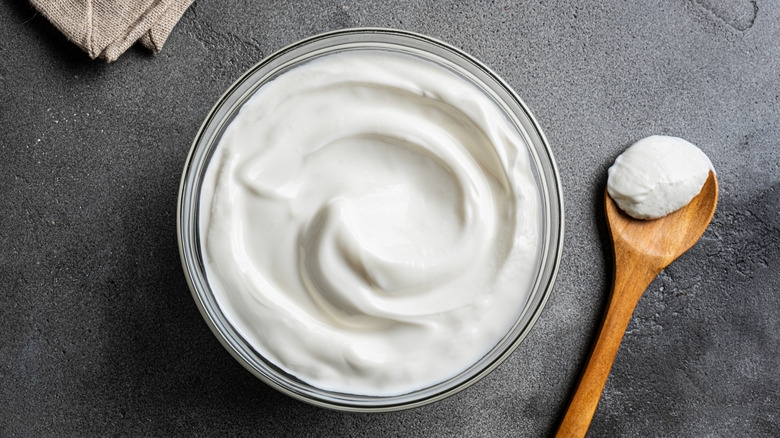 Greek yogurt in bowl with wooden spoon