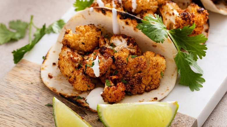 Roasted cauliflower taco with cilantro and lime wedges