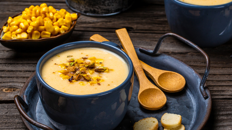 cup of corn soup with roasted corn in background