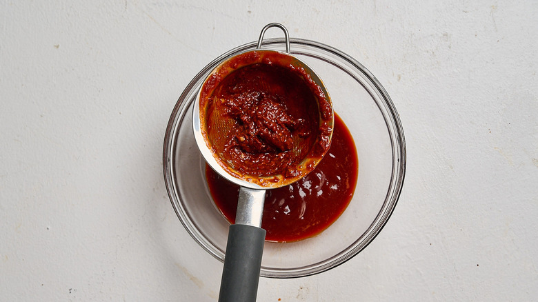 straining enchilada sauce through a strainer
