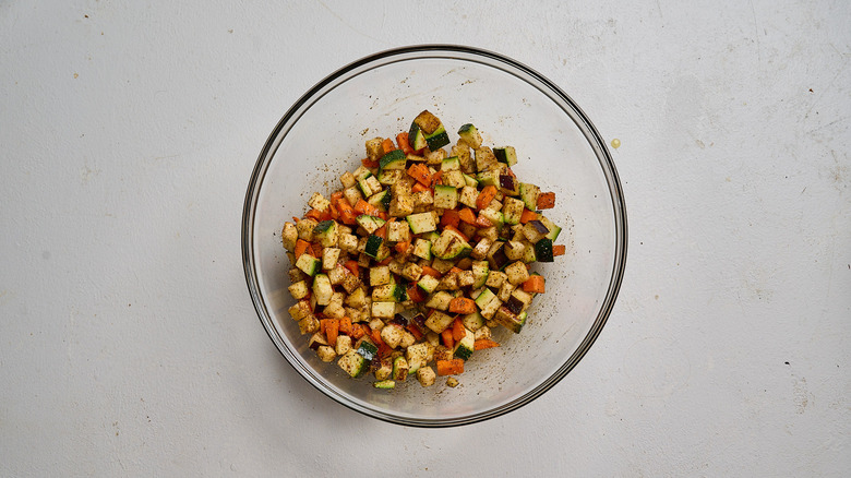 tossing vegetables with seasonings in a bowl