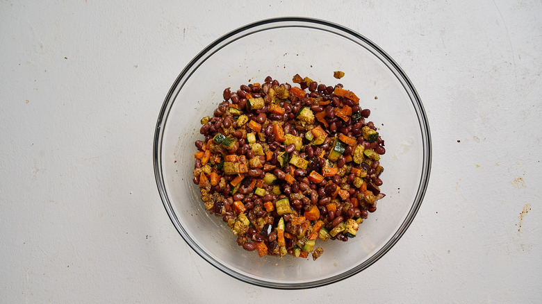 combining vegetables with beans in a bowl