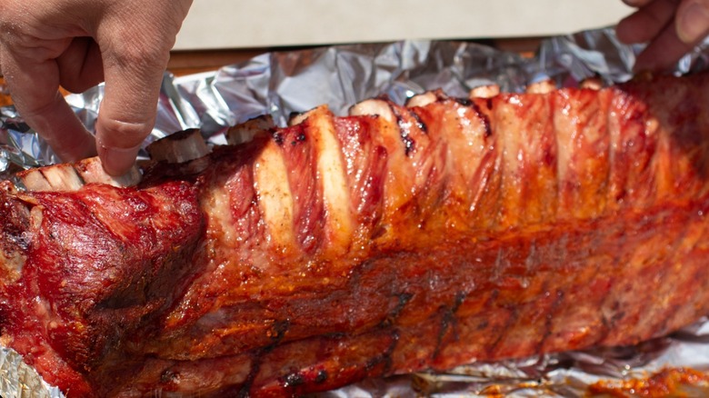person unwrapping ribs from foil
