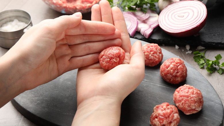 Person shaping meatballs with hands