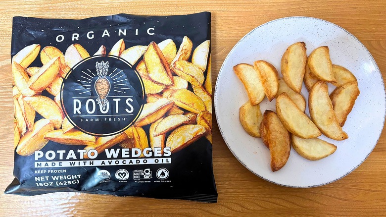 Roots Potato Wedges bag next to potato wedges on white plate