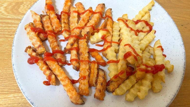 Roots Farm Fresh crinkle cut classic and sweet potato fries with drizzle of ketchup on white plate