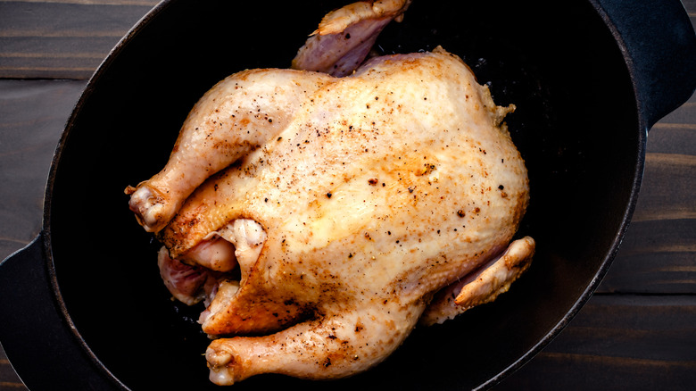 A cooked chicken sitting inside a Dutch oven