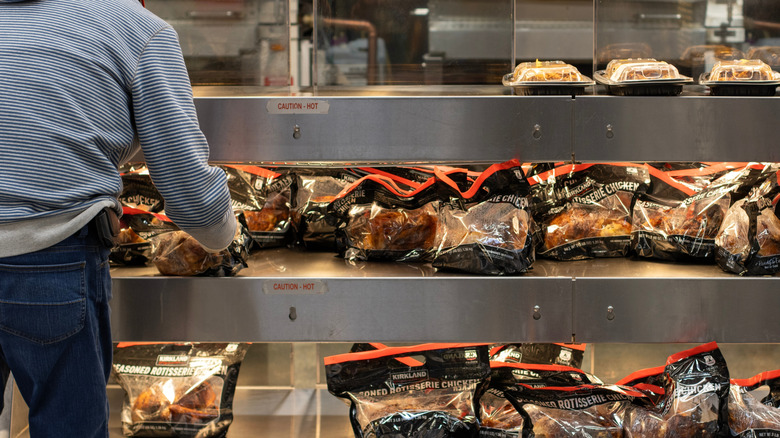 Packaged Costco rotisserie chickens under heat lamps.