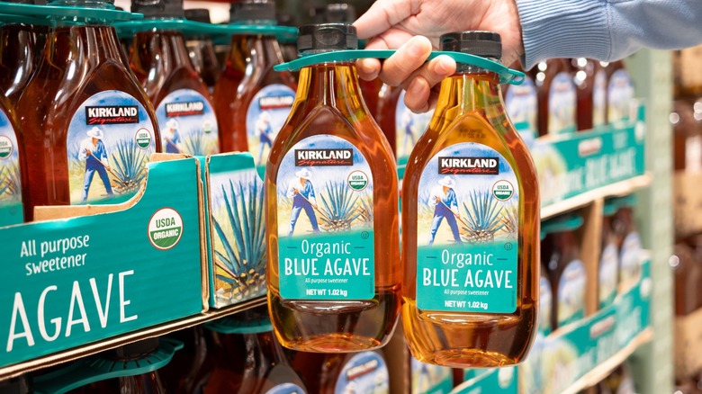 shopper holding Kirkland Signature Organic Blue Agave bottles from Costco