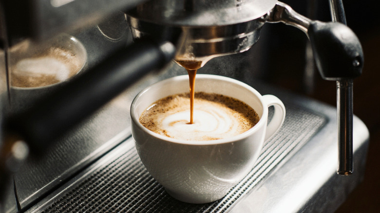 Close-up of a coffee machine pouring an espresso into a white cup.